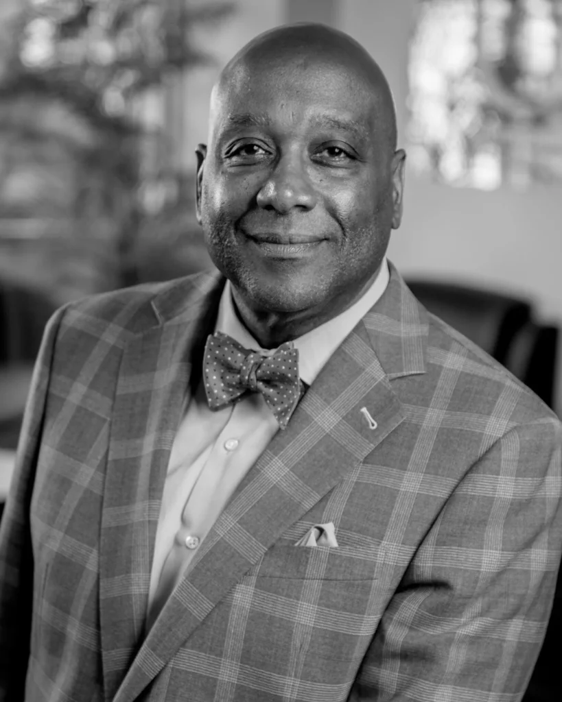 Smiling man in plaid suit jacket and bow tie, black and white portrait